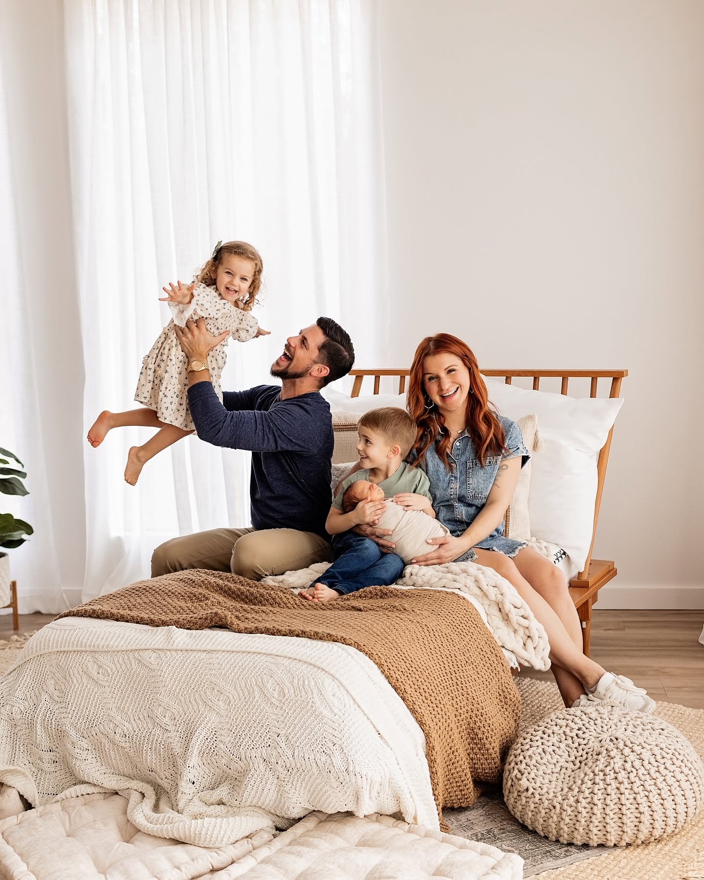 Our family laughing together on a bed in a bright, sunlit bedroom