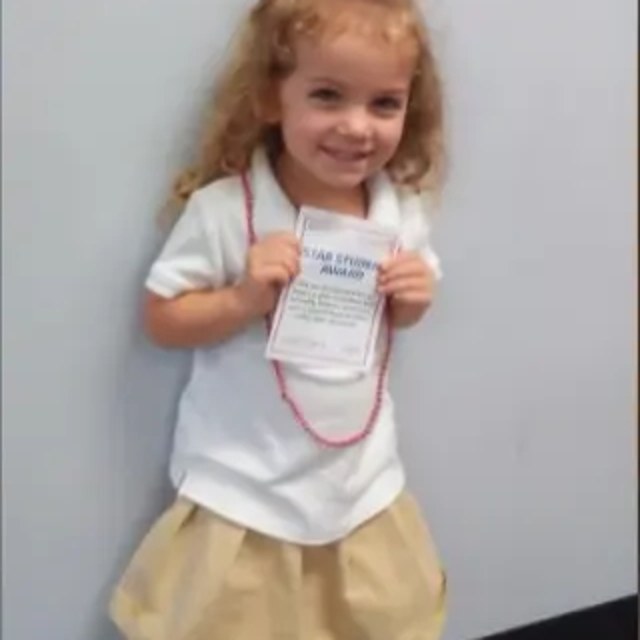 Proud little one holding a school award